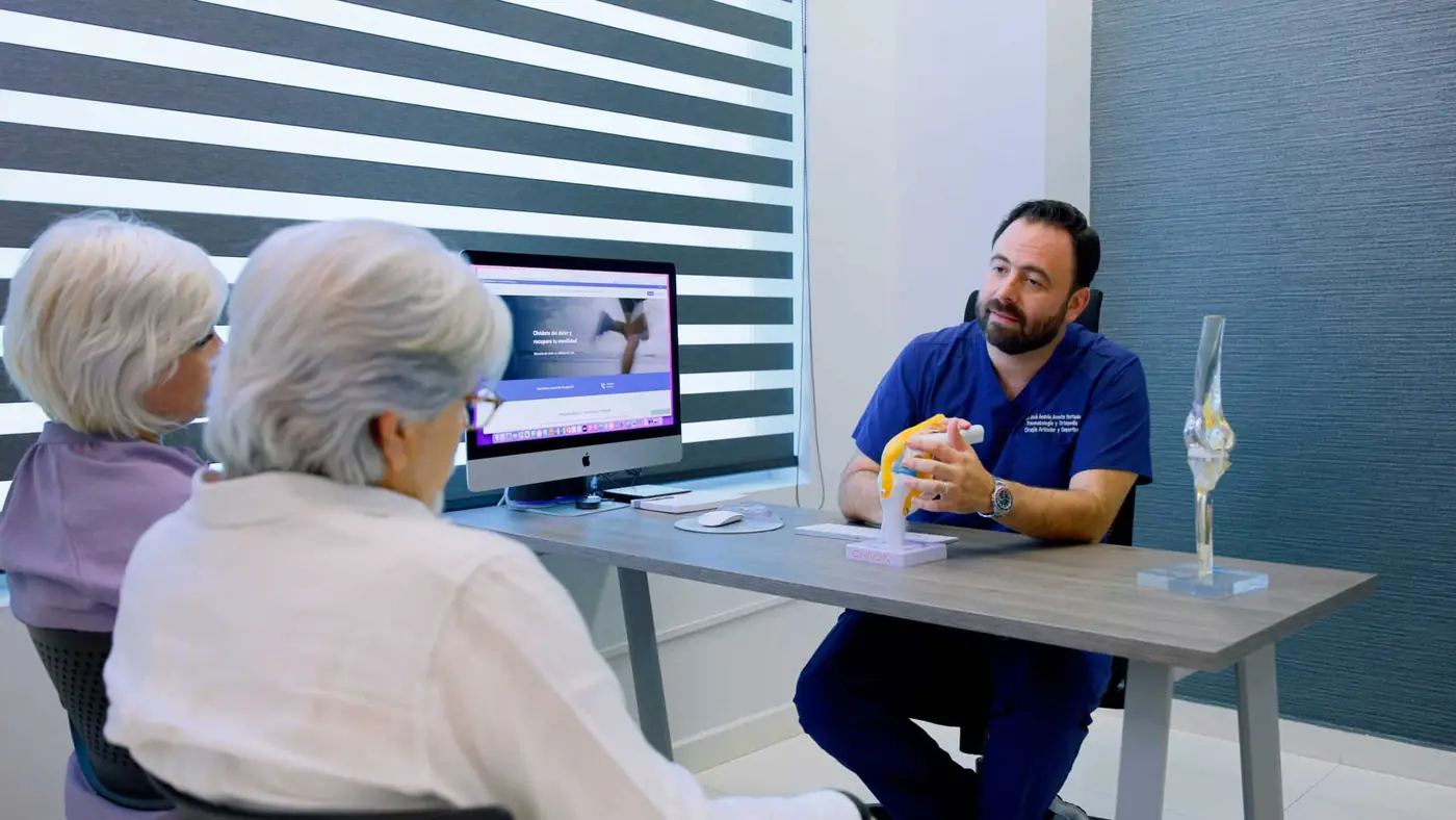 El Dr. Andrés Acosta revisando con una paciente los estudios de su rodilla durante la consulta